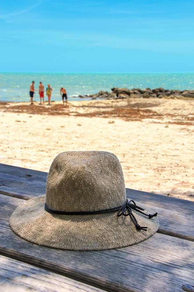 A hat lying on a bench at Fort Zachary Taylor Historic State Park at Key West with ocean in the distance